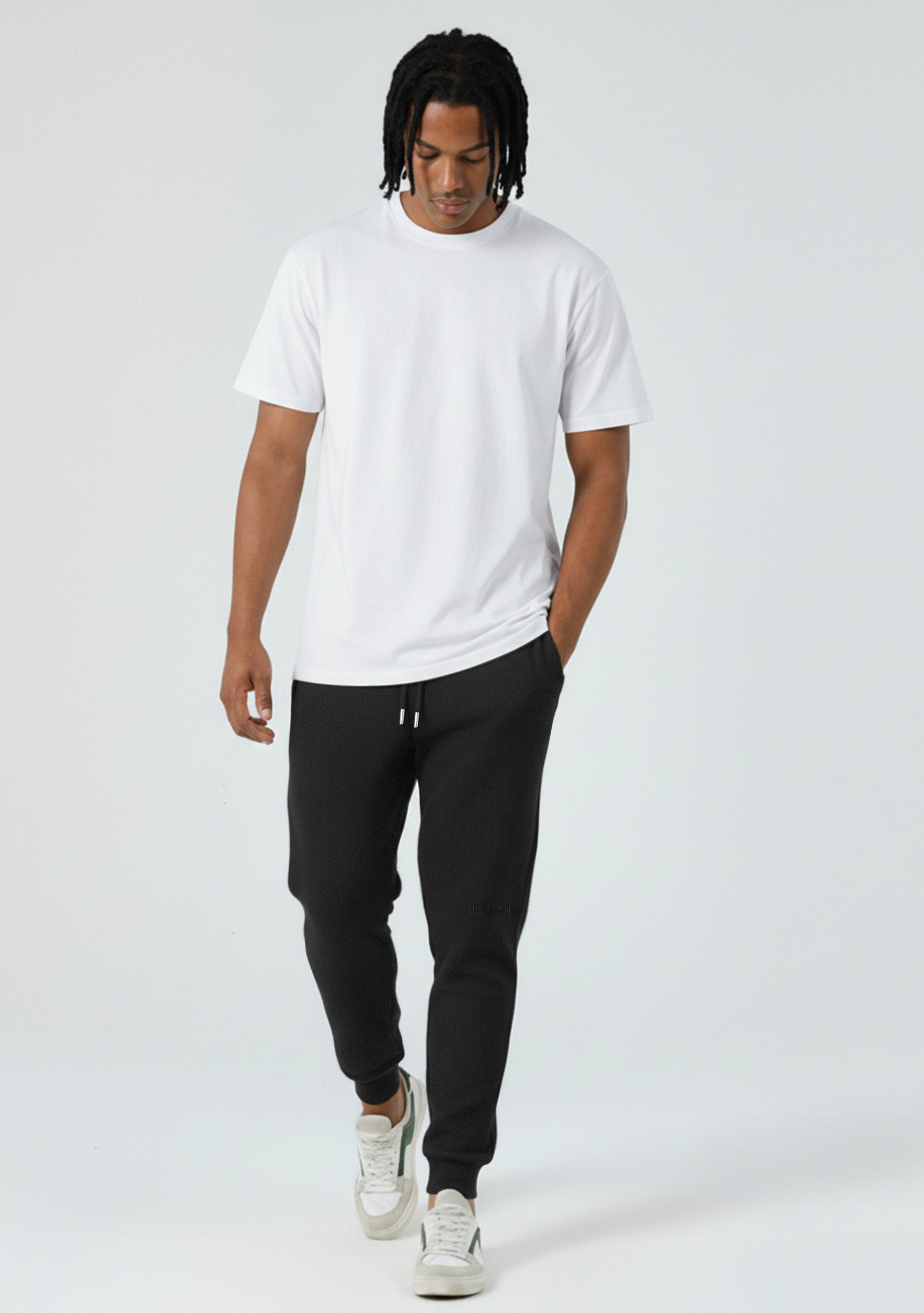 Model walking in the Herman men's black tapered joggers showing the slim fit.