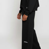 Close-up side view of the Herman men's black wide-leg joggers showing the logo detail.