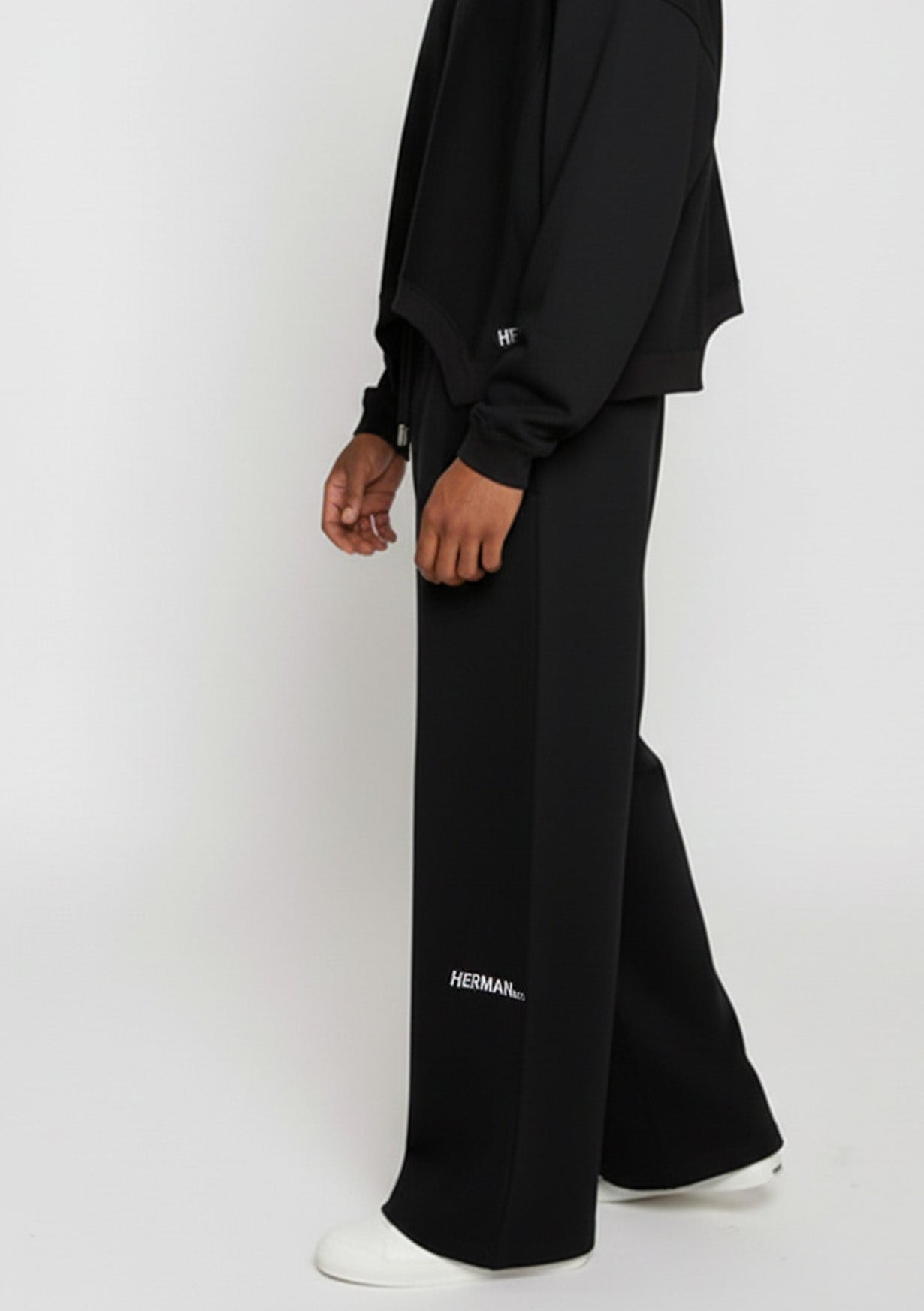 Close-up side view of the Herman men's black wide-leg joggers showing the logo detail.