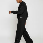 Side profile of a model walking in the Herman men's black wide-leg joggers.