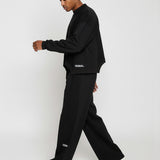 Side profile of a model walking in the Herman men's black wide-leg joggers.