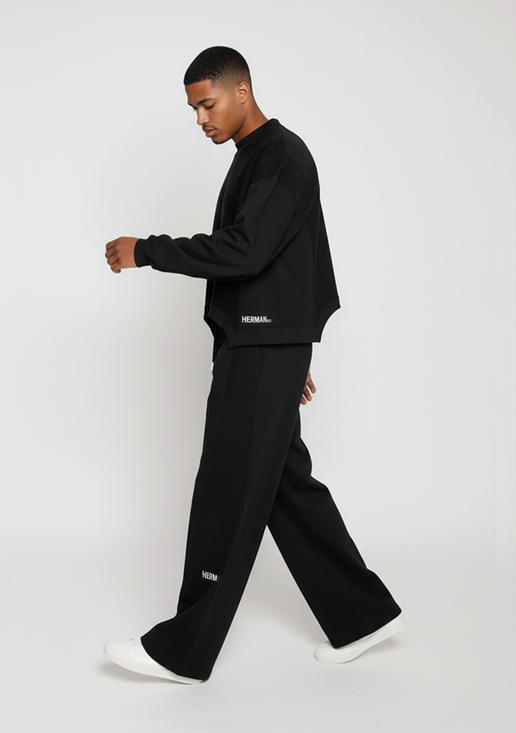 Side profile of a model walking in the Herman men's black wide-leg joggers.