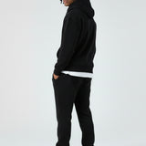 Side view of a model in the Herman men's black zip up hoodie and matching joggers