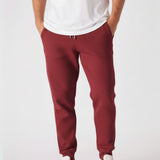 Front view of the Herman men's burgundy tapered joggers styled with a white t-shirt.