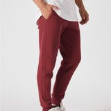 Side profile of a model wearing the Herman men's burgundy tapered joggers.