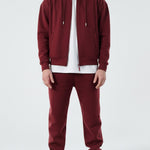 Model wearing the Herman men's burgundy zip hoodie as part of a full tracksuit.