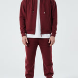 Model wearing the Herman men's burgundy zip hoodie as part of a full tracksuit.