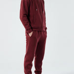 Side view of a model in the Herman men's burgundy zip up hoodie and matching joggers.