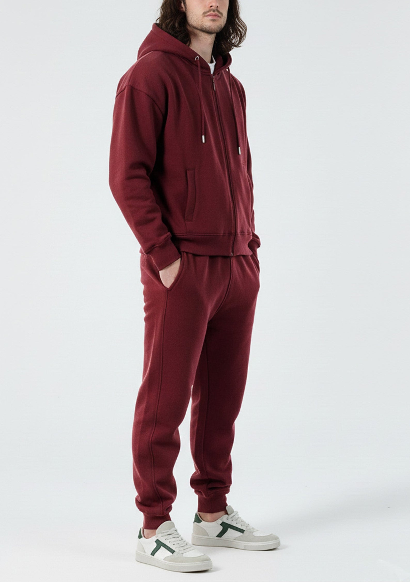 Side view of a model in the Herman men's burgundy zip up hoodie and matching joggers.