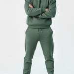 Model styled in the Herman men's green popper neck hoodie with arms crossed.