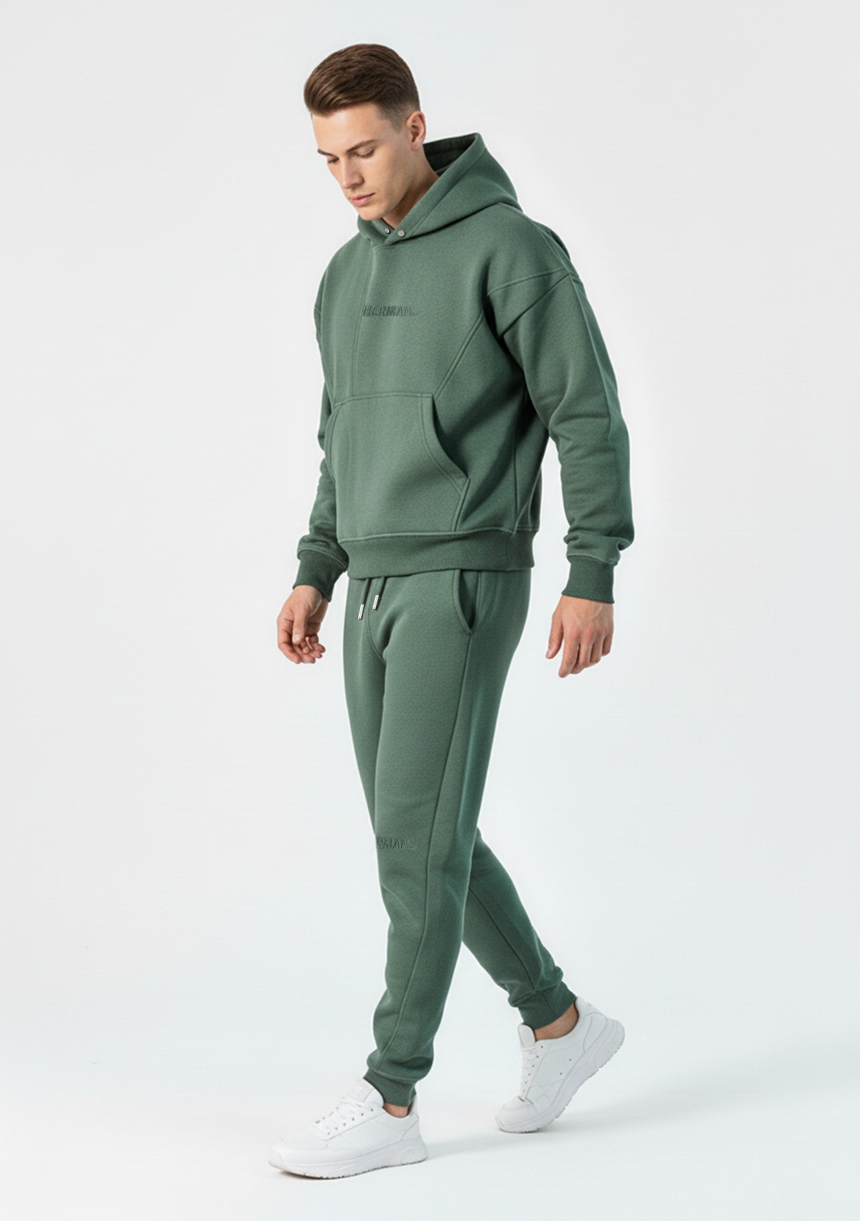 Side view of a model walking in the Herman men's green hoodie and joggers set.