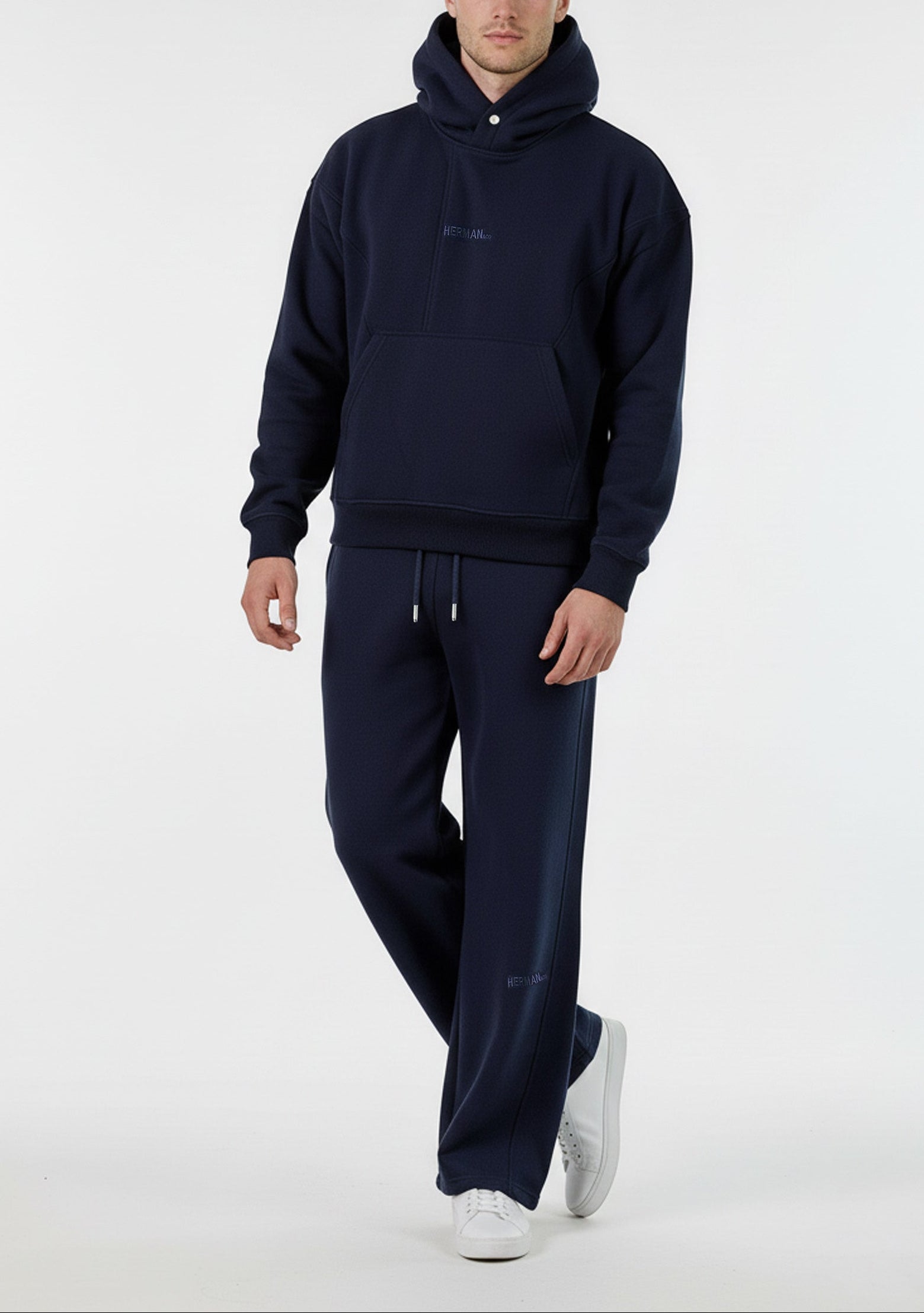 Angled front view of a model wearing the Herman men's navy popper neck hoodie and joggers set.