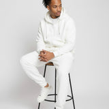 Model sitting while wearing the Herman men's white oversized zip hoodie and joggers set
