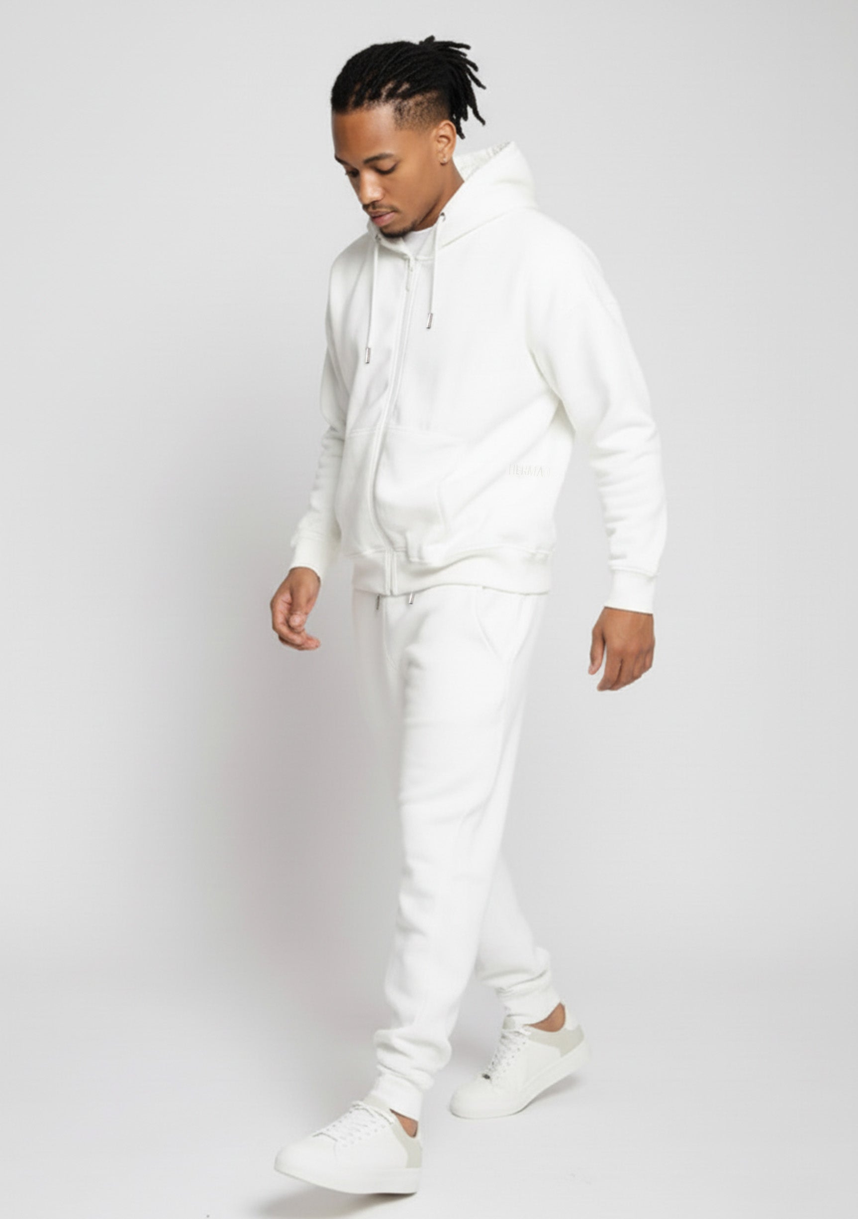 Full length side view of a model walking in the Herman men's white zip hoodie and joggers