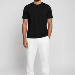 Model wearing Herman's essential men's white tapered joggers with a slim fit, styled with a black t-shirt