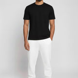 Model wearing Herman's essential men's white tapered joggers with a slim fit, styled with a black t-shirt