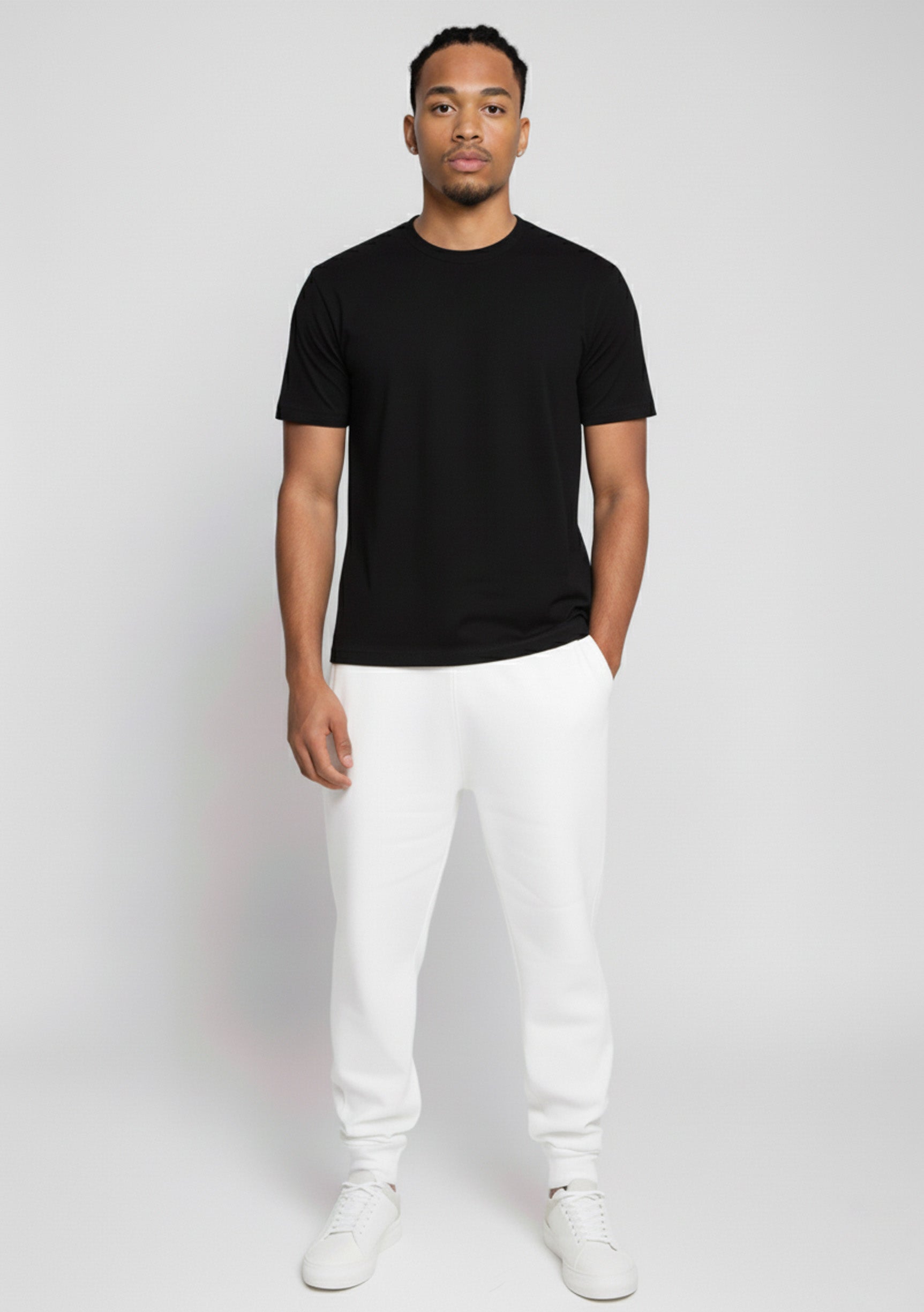 Model wearing Herman's essential men's white tapered joggers with a slim fit, styled with a black t-shirt