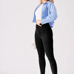 A side on shot of a model wearing high rise black jeggings for women with heels.