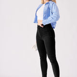 A side on shot of a model wearing high rise black jeggings for women with heels.