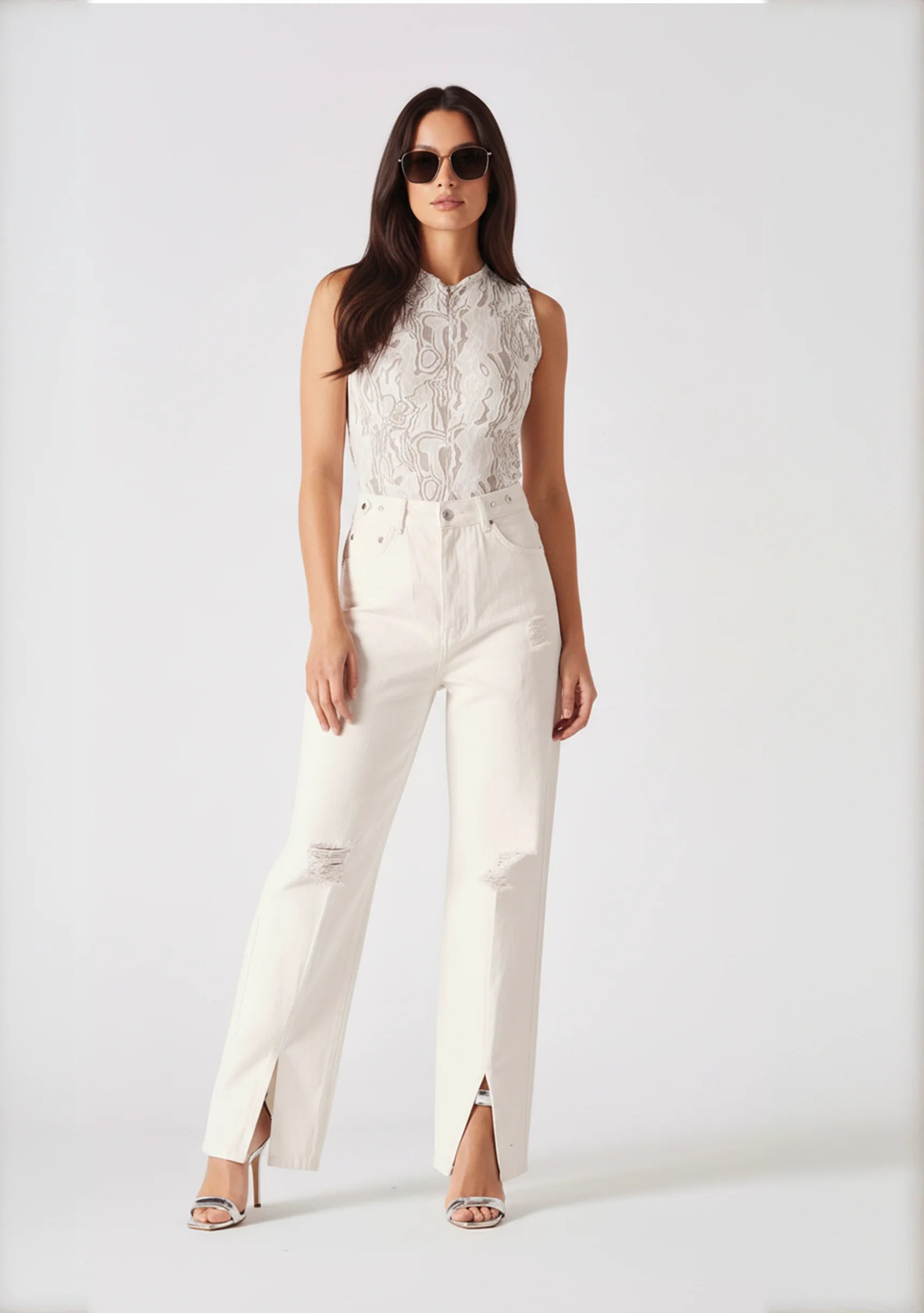 Full body studio shot of model standing in high-waist white jeans.