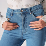 Close-up of the back pockets and logo patch on the high-waisted skinny jeans in blue.