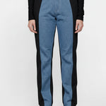 Full front view of a model wearing high-waisted two-tone straight jeans with black side panels.