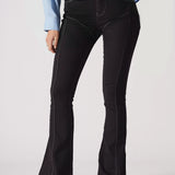 Person wearing black flared jeans and a light blue jacket on a white background