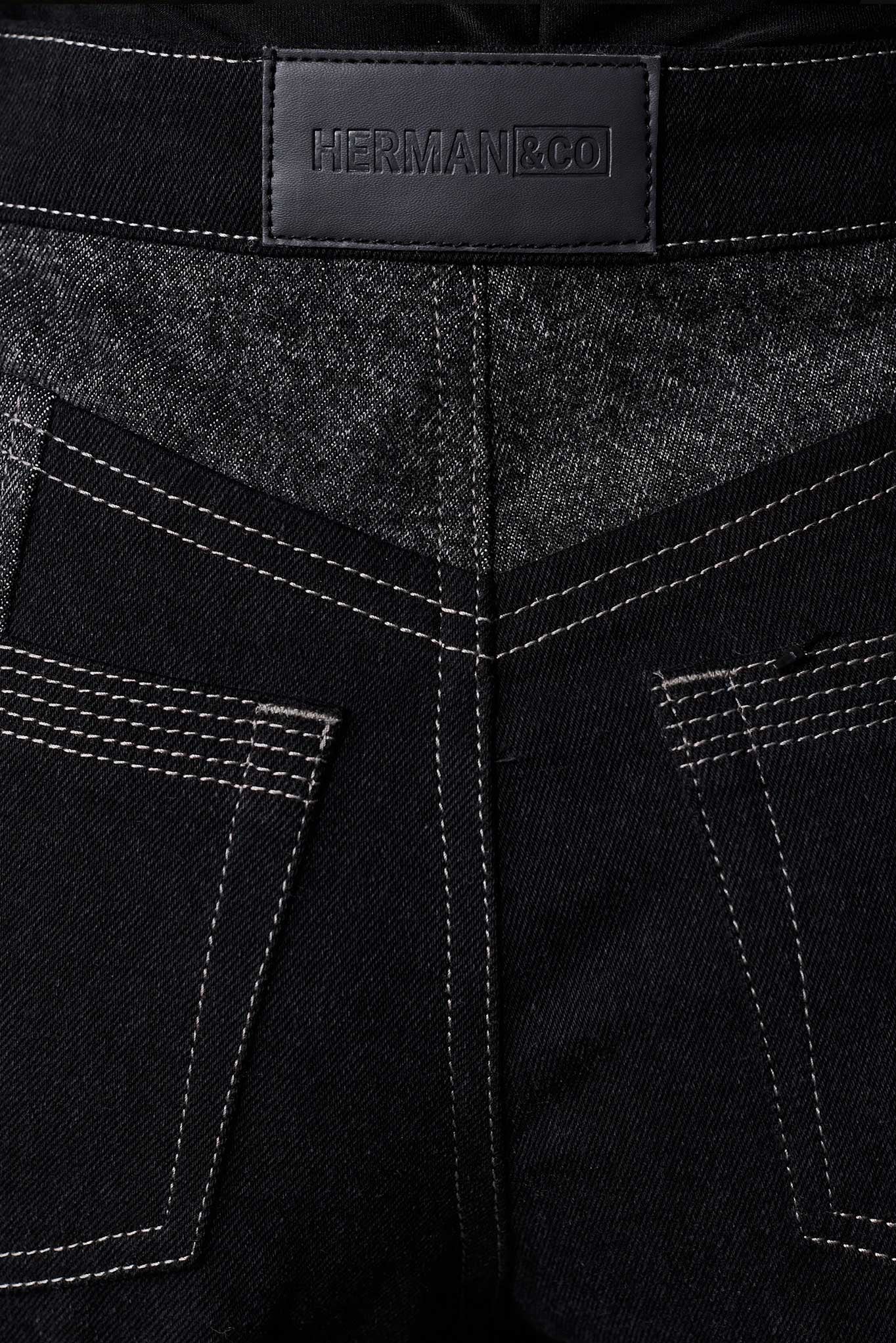 Close up of Herman and Co vegan leather branding patch and back patch pockets on black acid wash jeans