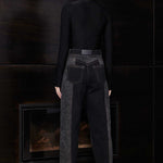 Back view of model wearing Jmojo black acid wash tapered jeans with vegan leather branding patch
