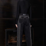 Back view of model wearing Jmojo black acid wash tapered jeans with vegan leather branding patch