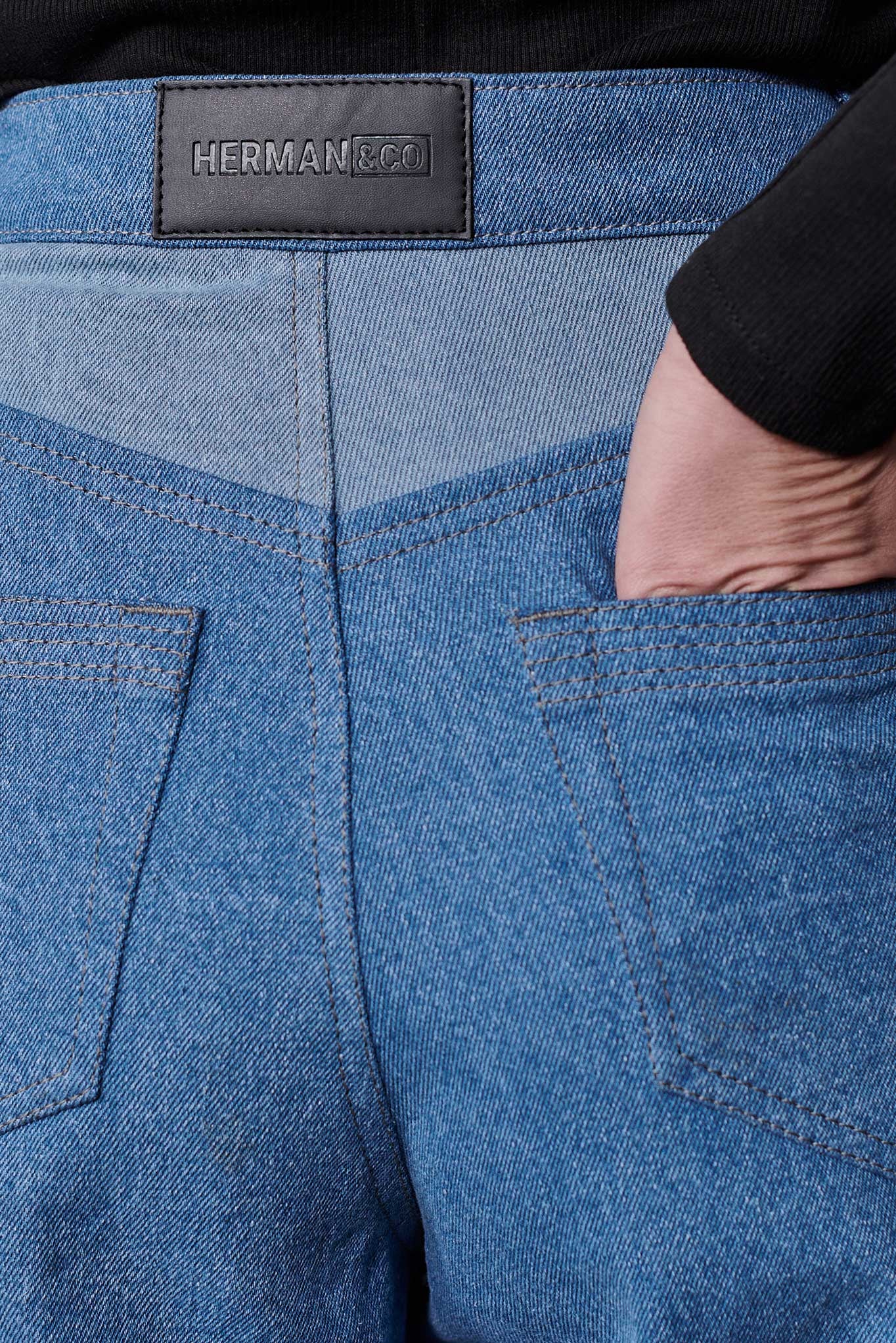 Close up of Herman and Co vegan leather branding patch and back pockets on blue wash tapered jeans