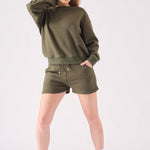 A front view of a woman wearing a khaki crew neck jumper with matching shorts and a headband