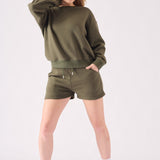 A front view of a woman wearing a khaki crew neck jumper with matching shorts and a headband