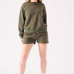 A woman posing in a khaki crew neck jumper with a white headband for a casual look
