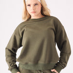 Mid shot of a model wearing a khaki crew neck jumper showing the relaxed fit and ribbed trims