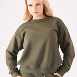 Mid shot of a model wearing a khaki crew neck jumper showing the relaxed fit and ribbed trims