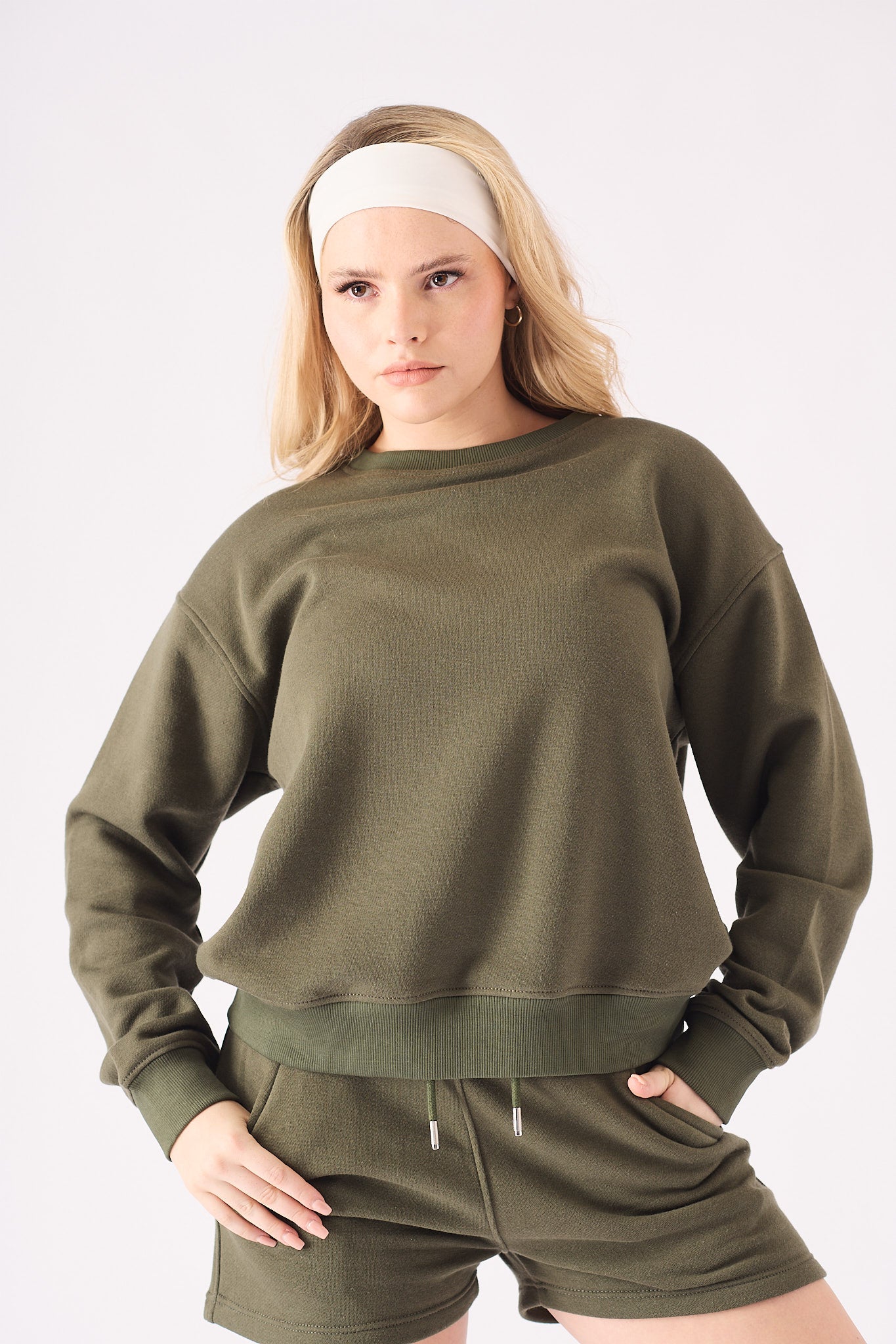 Mid shot of a model wearing a khaki crew neck jumper showing the relaxed fit and ribbed trims