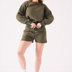Close up front view of the soft fabric and waist of a khaki crew neck jumper