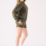 Side profile view of a woman wearing a comfortable khaki crew neck jumper