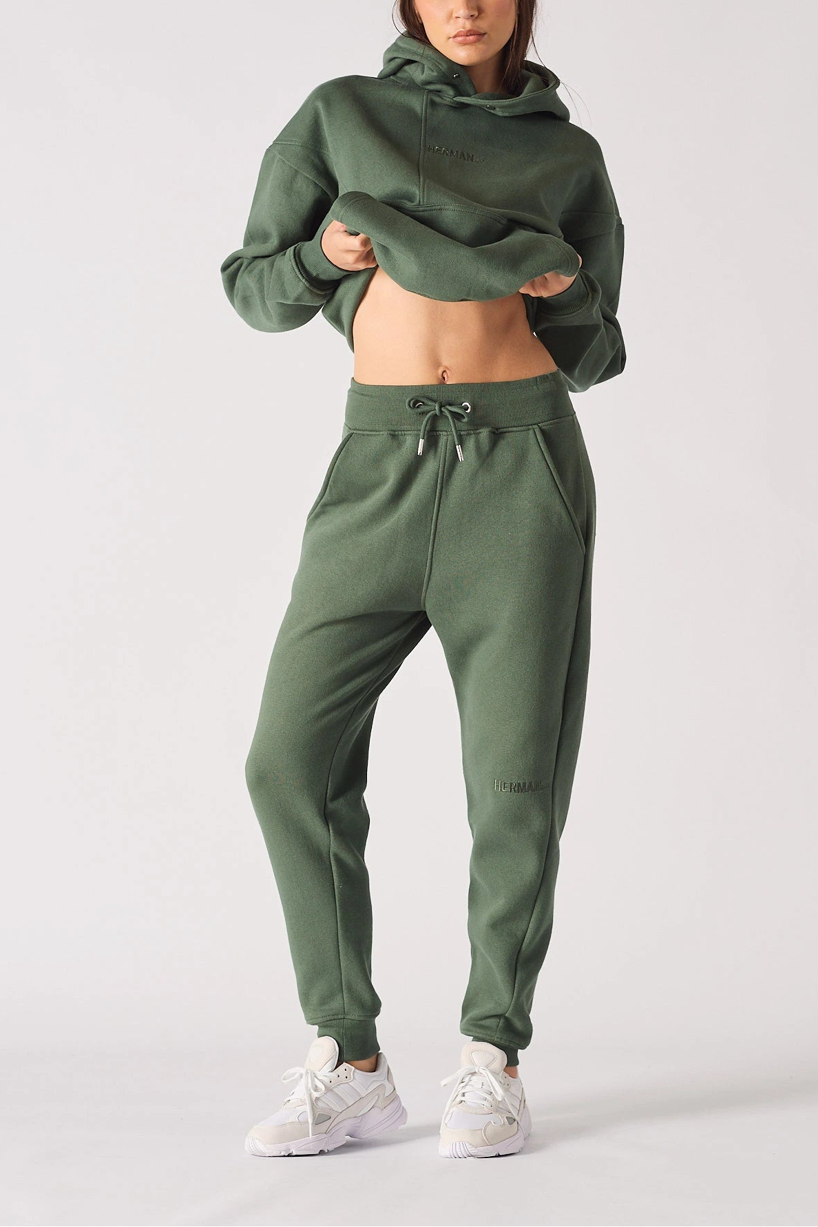 Full body front shot of a model wearing khaki green joggers women and matching hoodie.