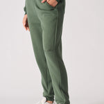 A model walking while wearing premium khaki green joggers women and white trainers.