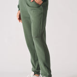 A model walking while wearing premium khaki green joggers women and white trainers.