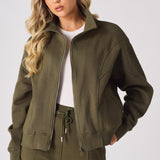 A model posing in a khaki zip up sweatshirt with a white t shirt underneath
