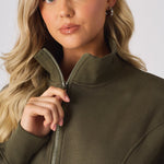 Close up of a hand adjusting the zip on a khaki funnel neck sweatshirt
