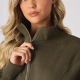 Close up of a hand adjusting the zip on a khaki funnel neck sweatshirt