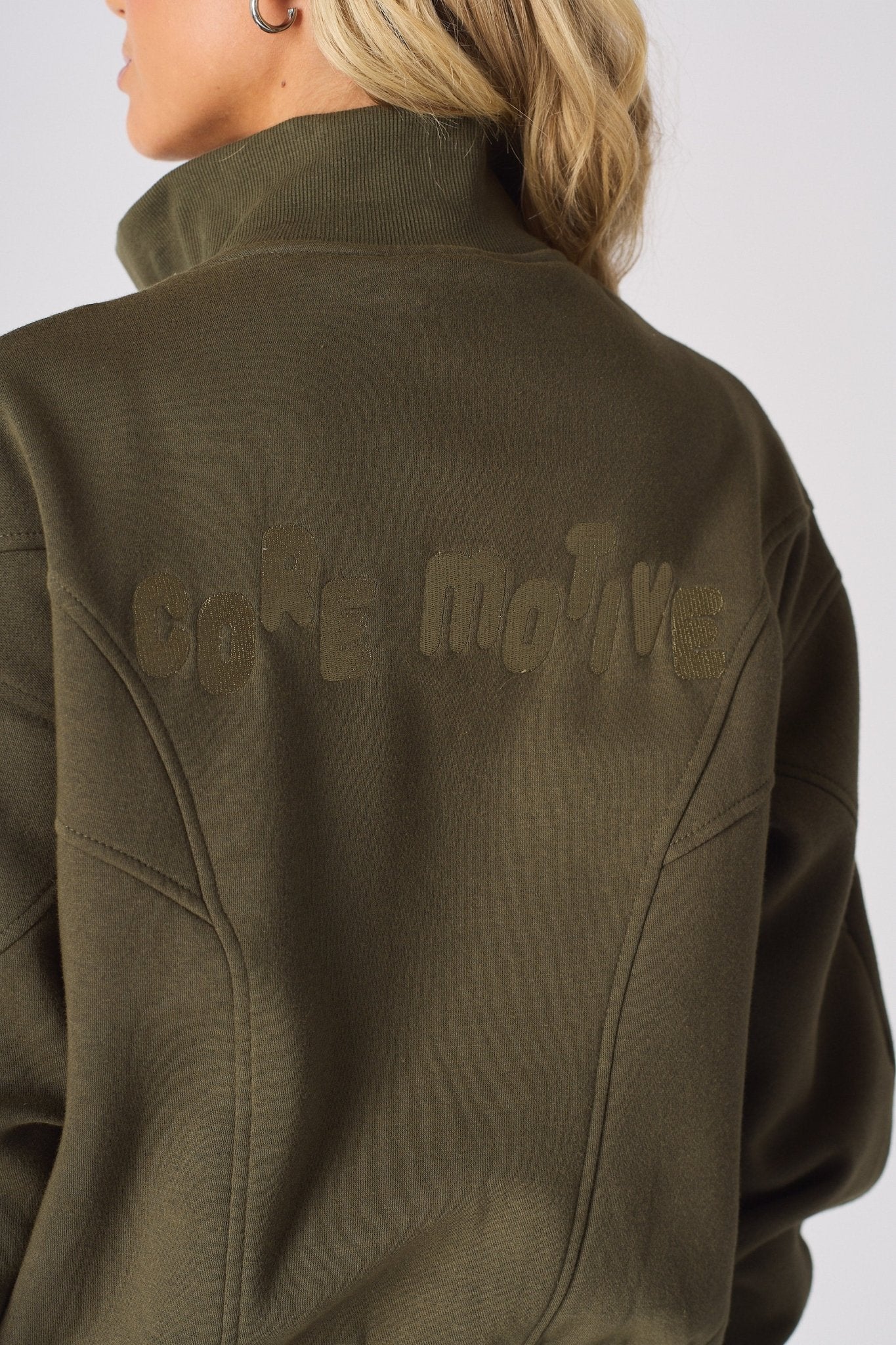 Detailed shot of the tonal embroidered branding on the back of a khaki sweatshirt