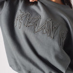Detailed shot of the high quality fabric and embroidery on the ladies oversized grey sweatshirt.