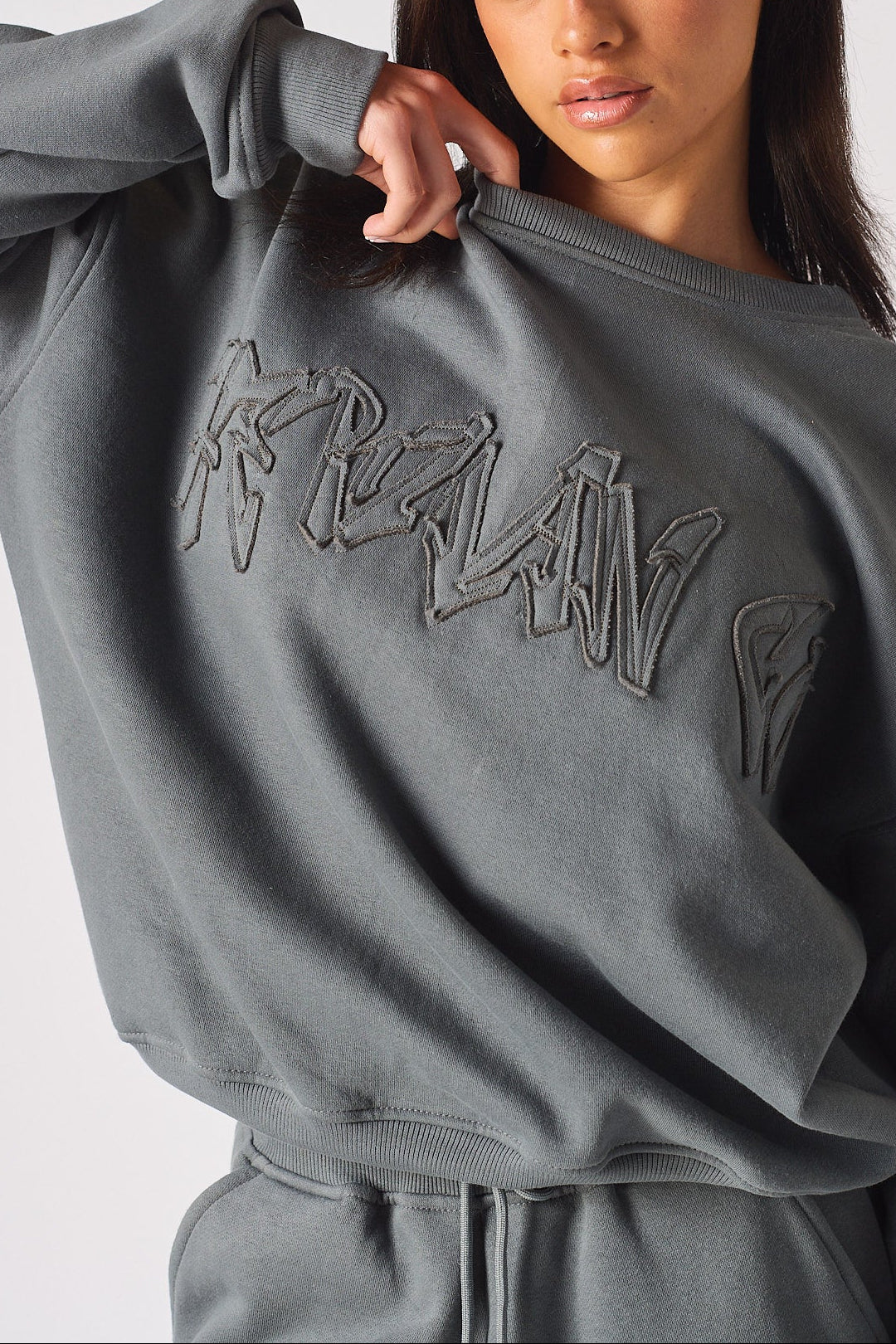 Detailed shot of the high quality fabric and embroidery on the ladies oversized grey sweatshirt.