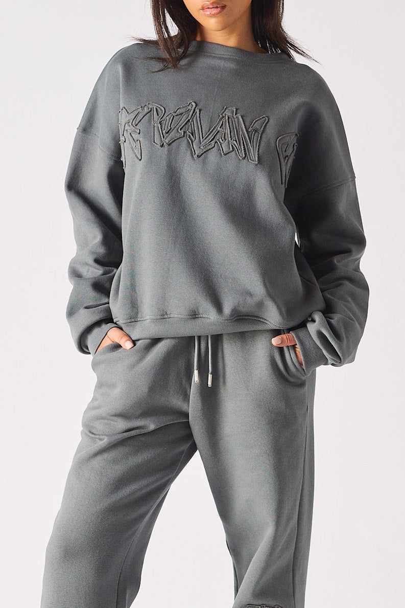 A woman wearing a stylish ladies oversized grey sweatshirt with tonal embroidery.