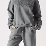 A woman wearing a stylish ladies oversized grey sweatshirt with tonal embroidery.